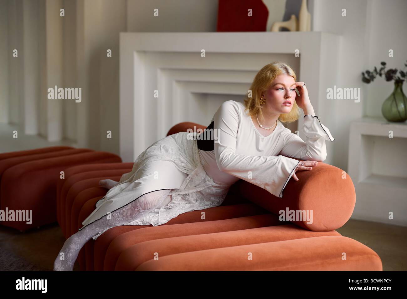 Stilvolle Frau in elegantem Outfit, die auf einzigartigen Möbeln liegt Stockfoto