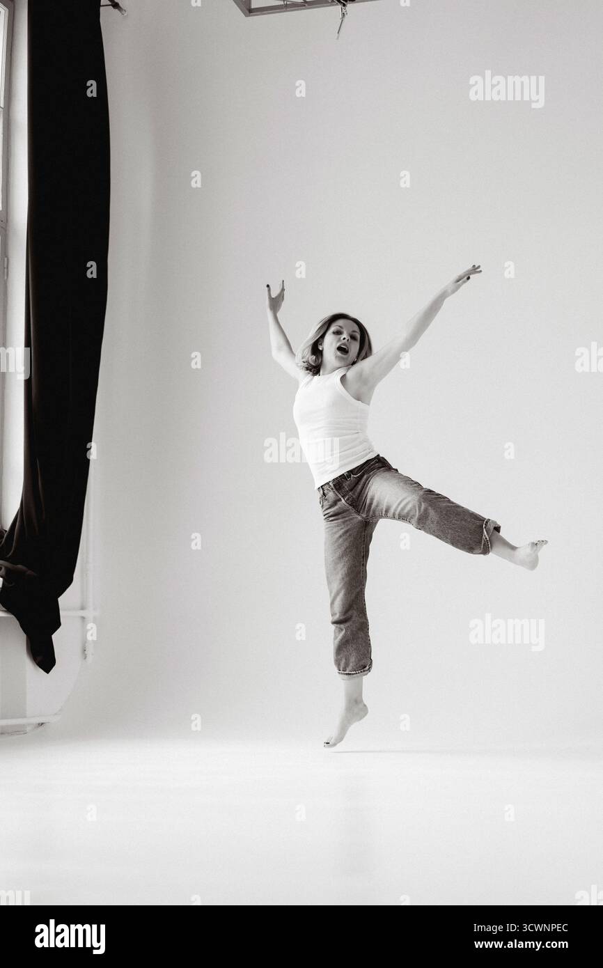 Glückliche Frau, die vor Freude im Studio springt, schwarz auf weiß Stockfoto