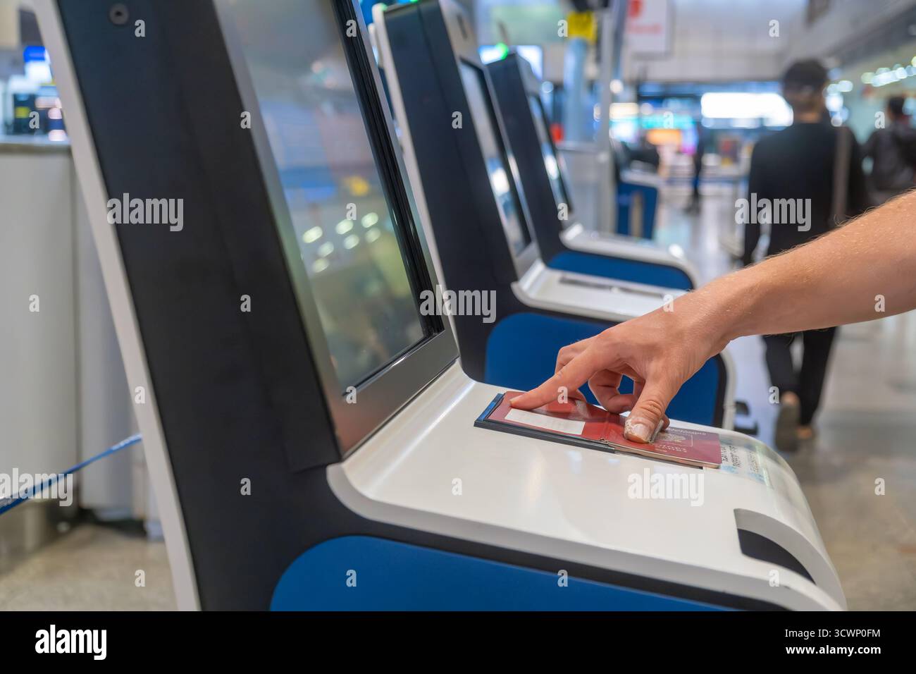 Reisende scannen ihren Reisepass am Check-in-Automaten im modernen Flughafenterminal. Automatisierte Maschine für einfache und effiziente Flugreisen Stockfoto