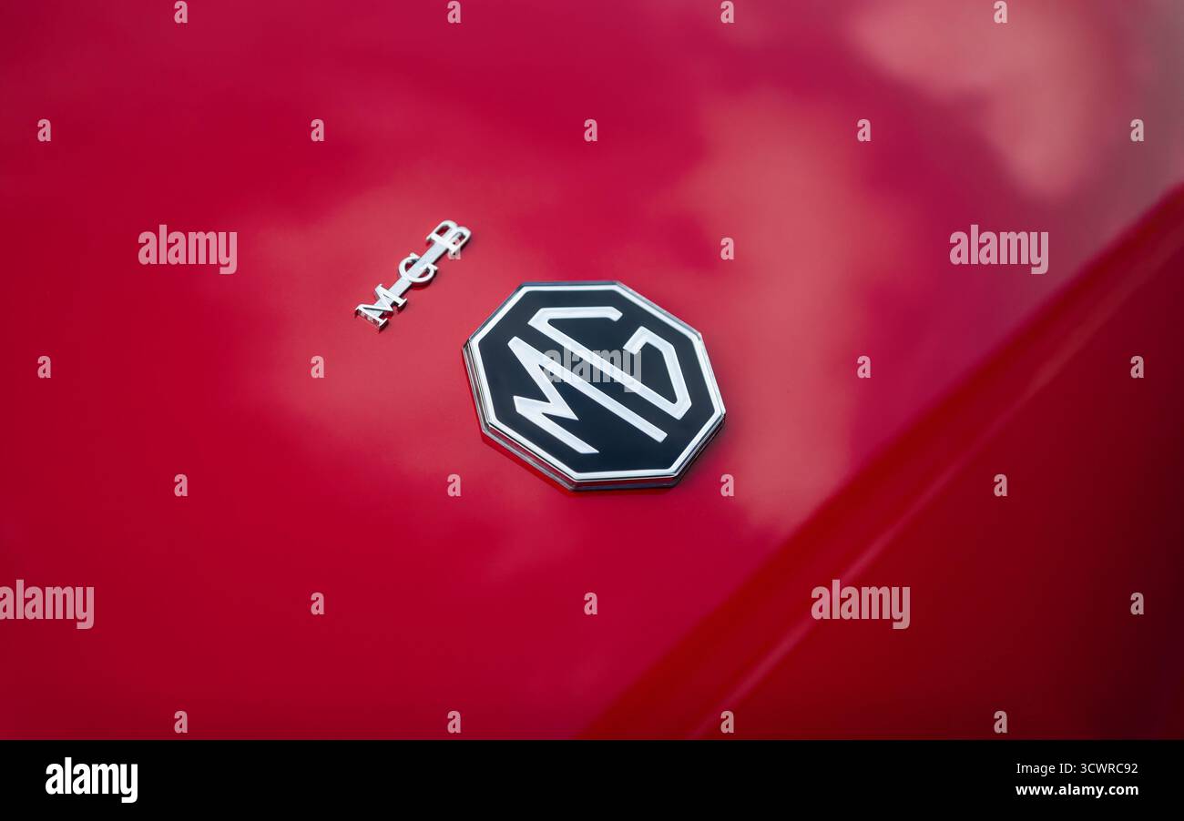MG-Logo auf rotem Auto – Nahaufnahme. Achteckiges britisches Autoemblem auf dem Kofferraum des MGB Roadsters aus den 1960er Jahren. Stockfoto