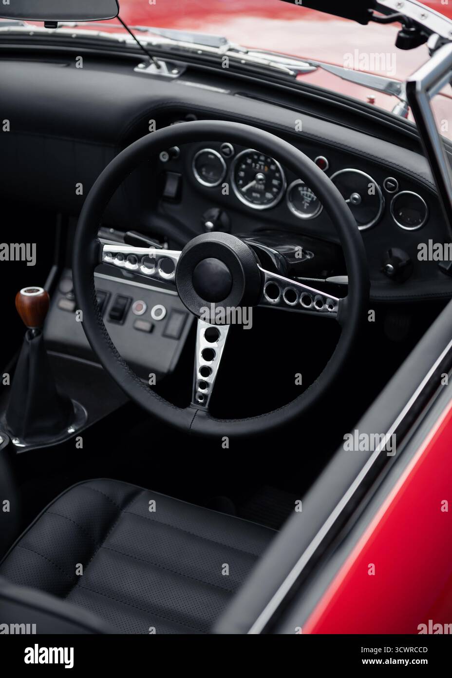 Innenraum eines Sportwagens mit offenem Oberdeck für Rechtslenkung. Roter Oldtimer mit schwarzem Lederinnenraum. Stockfoto