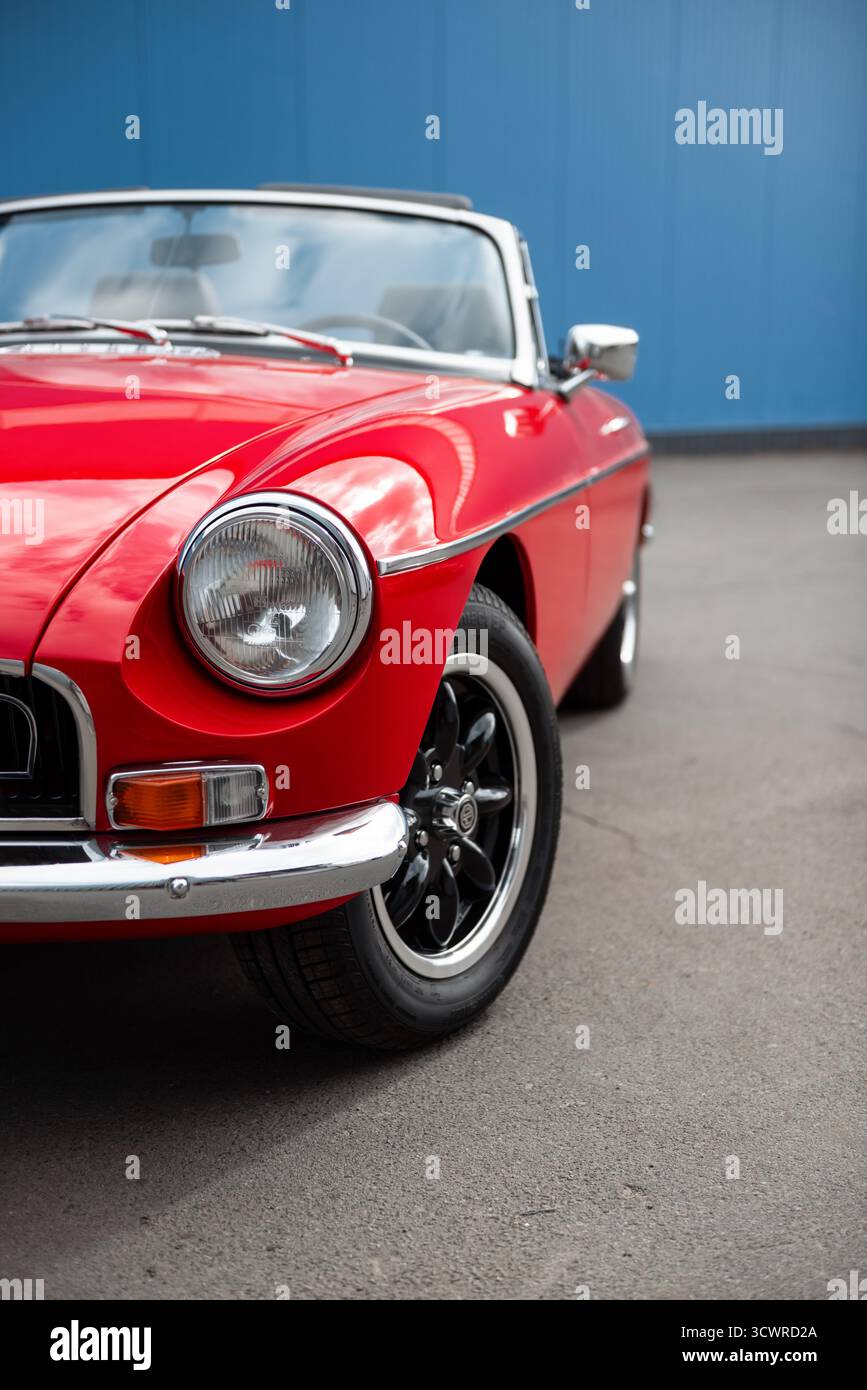 Vorderansicht links des alten roten 1960er-MG-Roadsters. Klassischer MGB-Sportwagen auf der Stadtstraße – Nahaufnahme von Scheinwerfer, Kotflügel, Motorhaube und Rad Stockfoto