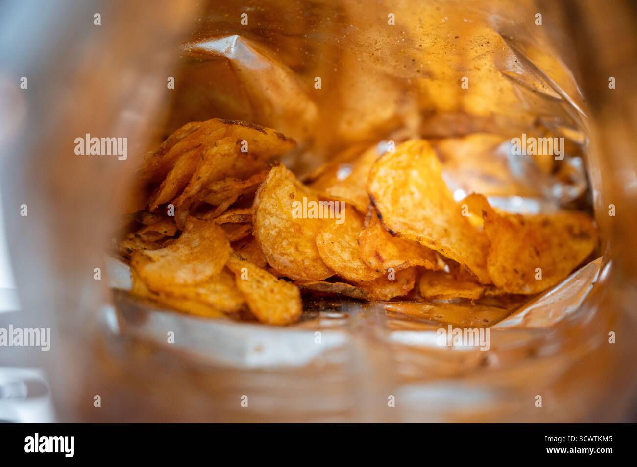 Offene Tüte Kartoffelchips mit knusprigen goldenen Scheiben – verführerischer salziger Snack, der sowohl schmackhaften Genuss als auch ungesunde Junkfood-Gewohnheiten symbolisiert Stockfoto