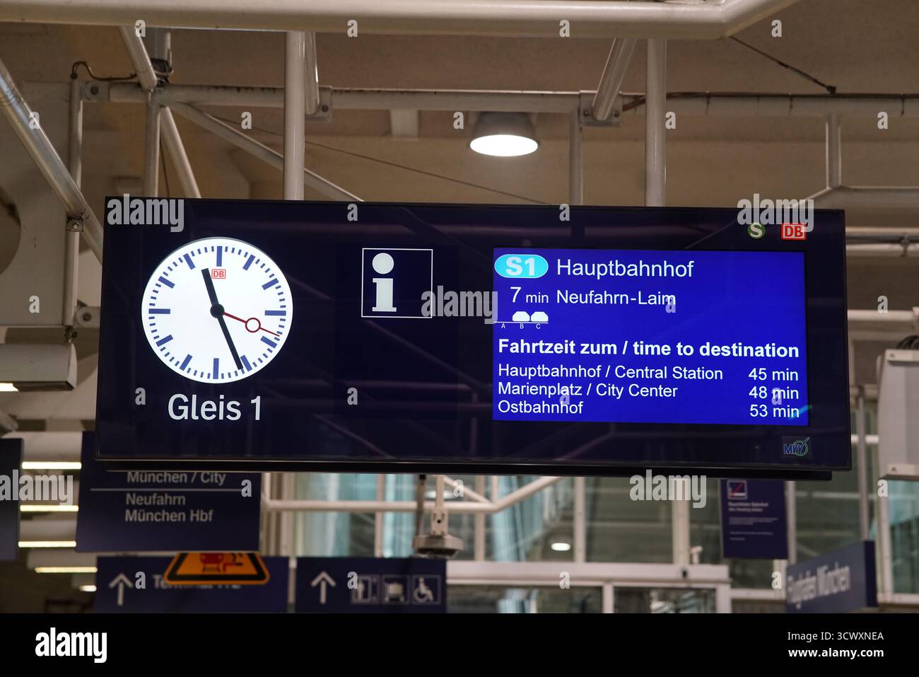 Digitale S-Bahn-Abfahrtstafel München mit Uhr, die den Zug S1 zum Hauptbahnhof an Bahnsteig 1 in einem modernen deutschen Bahnhof anzeigt. München, Deutschland Stockfoto