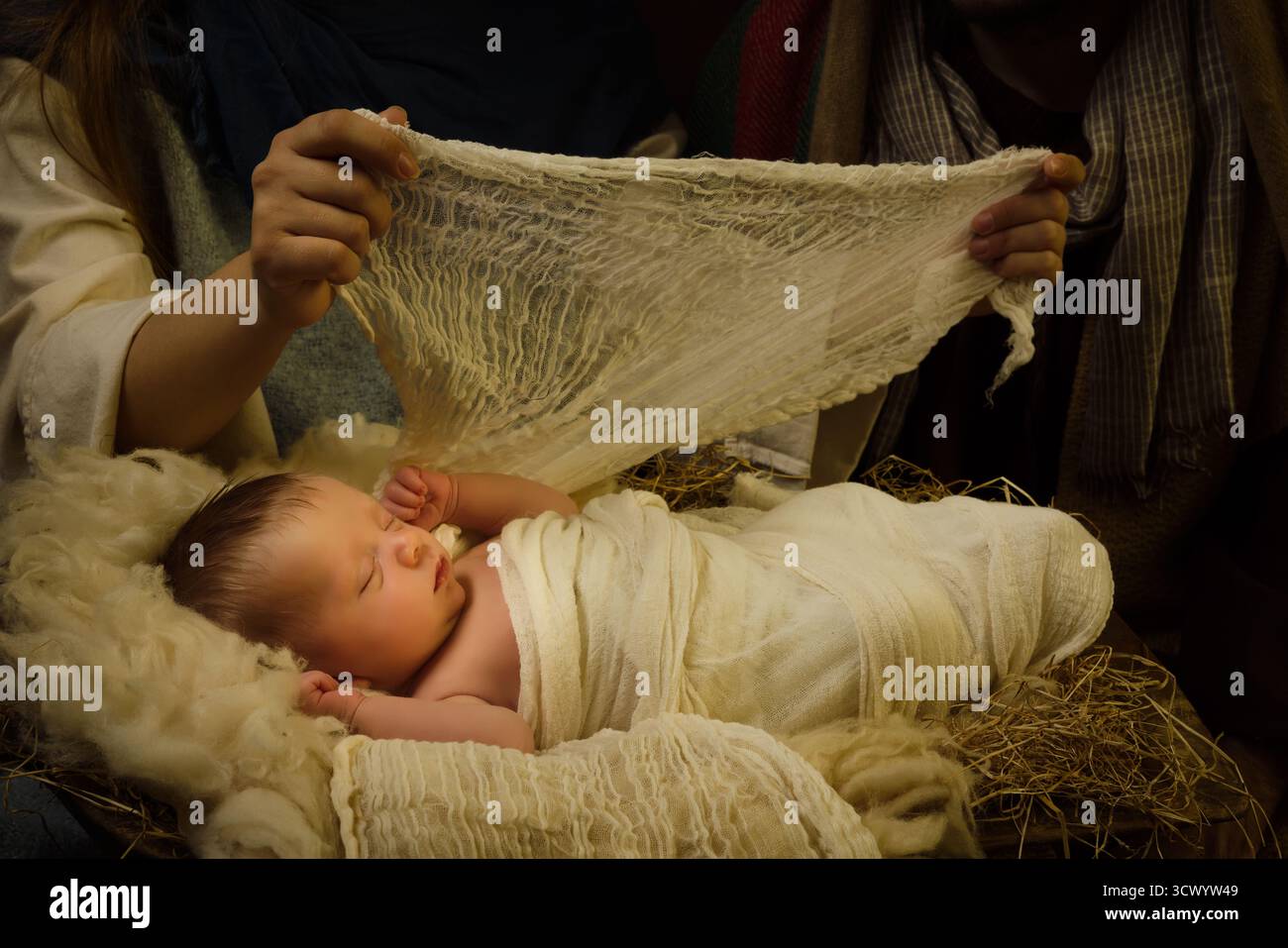 Die Hände von Mutter Maria, die das Jesuskind während einer weihnachtskrippe wickelt Stockfoto