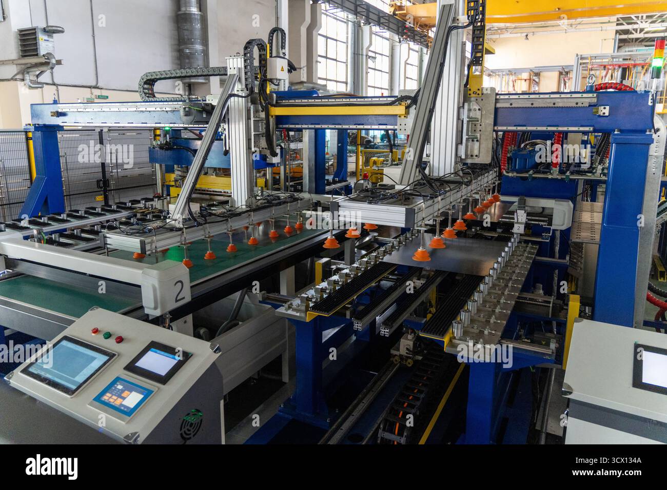 Eine moderne automatische Stanzmaschine in einer Kühlschrankproduktionslinie, die Roboterarme mit Vakuumgreifer zum Verschieben von Rückplatten verwendet. Ein Bedienfeld auf Stockfoto