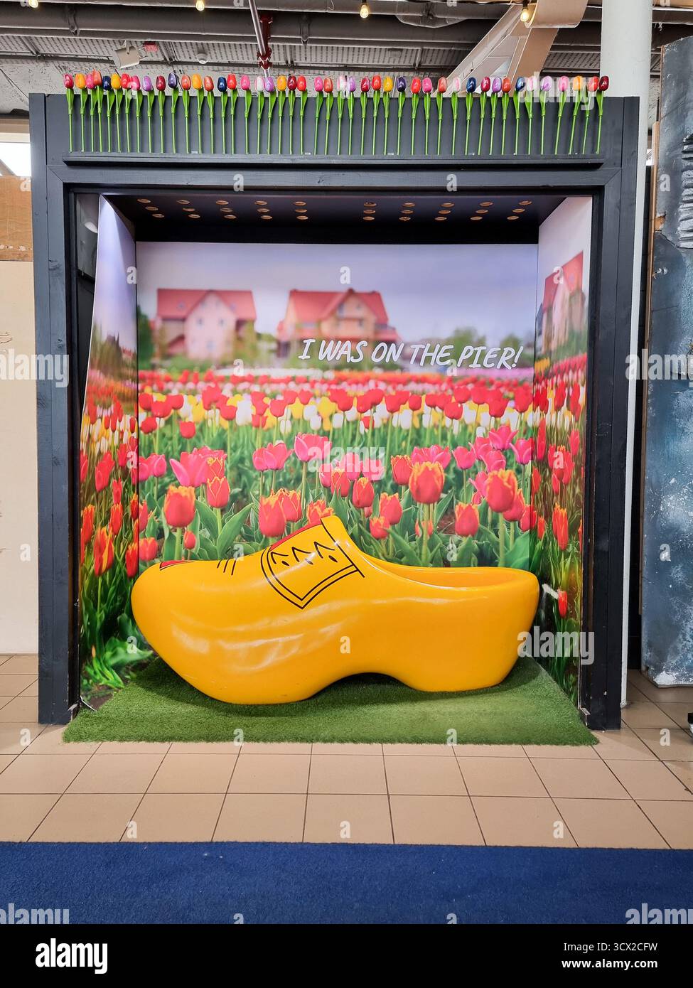 Fotogelegenheit, Stand, Lage mit großem gelben Holzschuh- und Tulpenhintergrund, traditionelles holländisches „I Was on the Pier“ Scheveningen, Niederlande - Smartphone-aufgenommenes Stockfoto