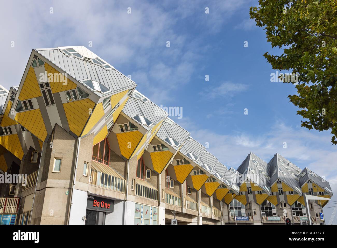 Die markanten und markanten Kubuswoningen in Rotterdam mit ihren geneigten, würfelförmigen Strukturen in Gelb und Grau gegen ein helles B Stockfoto