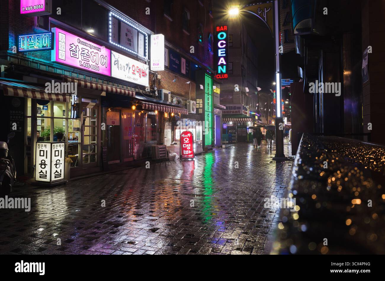 Busan, Südkorea - 19. März 2018: Nächtlicher Straßenblick mit farbenfroher Neonwerbung, Menschen und Autos sind auf der regnerischen Straße in der Innenstadt Stockfoto