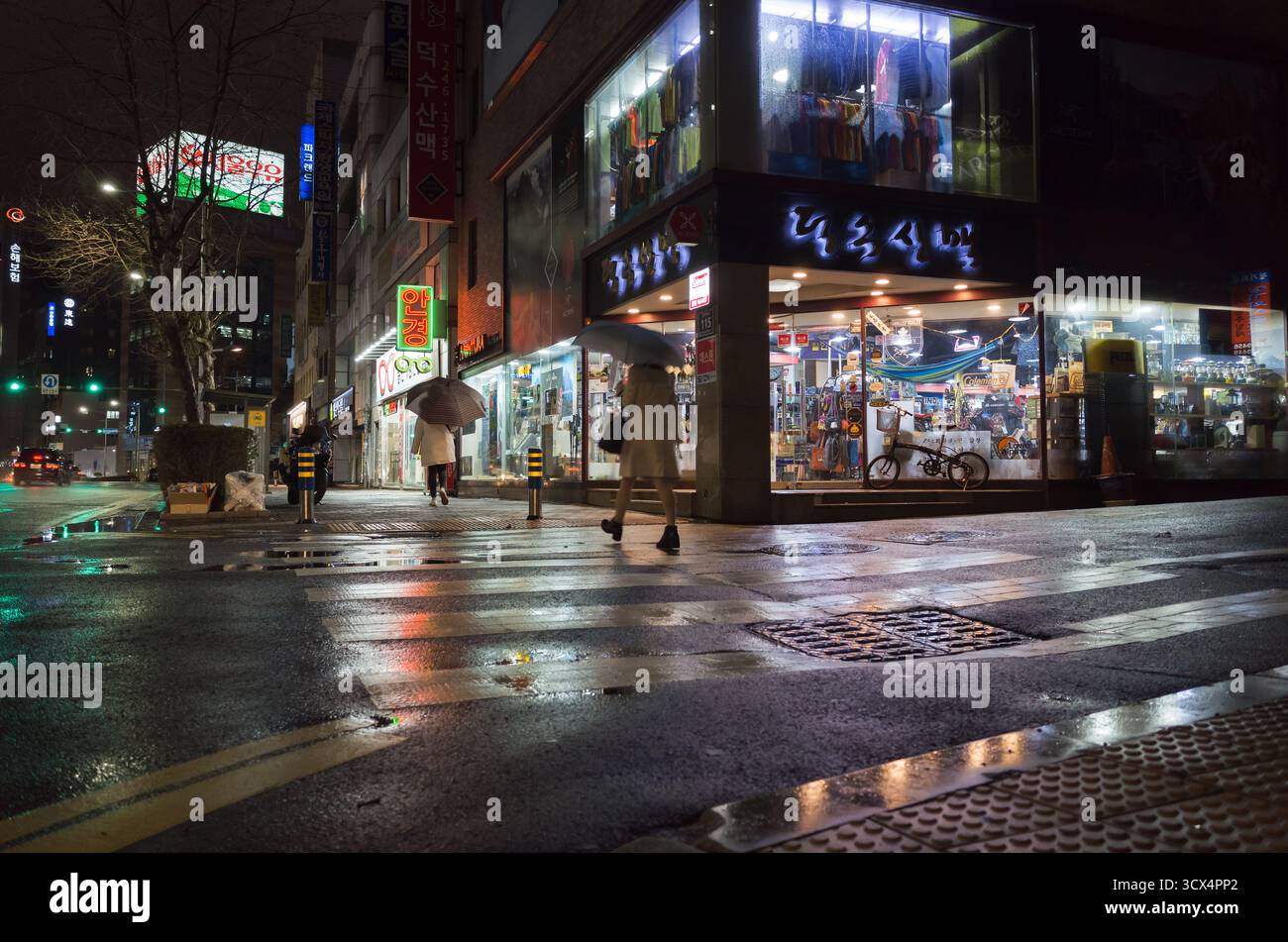 Busan, Südkorea - 19. März 2018: Nachtstraßenfotografie mit farbenfroher Neonwerbung. Die Leute laufen durch die regnerische Straße in der Innenstadt Stockfoto