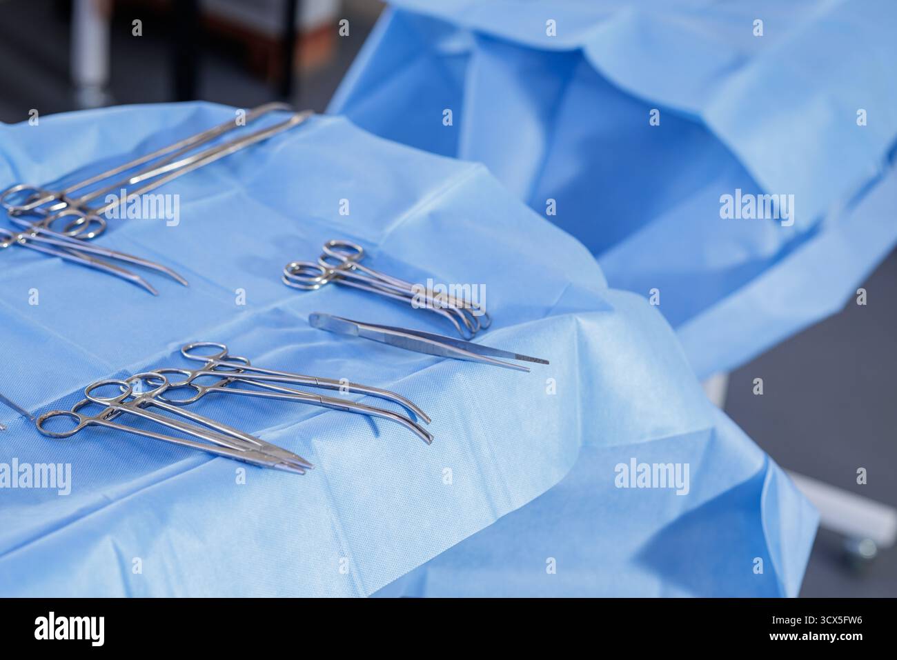 Nahaufnahme rostfreier chirurgischer Werkzeuge auf einem blauen sterilen Feld, einsatzbereit ideal für Schulungen im Gesundheitswesen und Sicherheitsmaterialien. Stockfoto