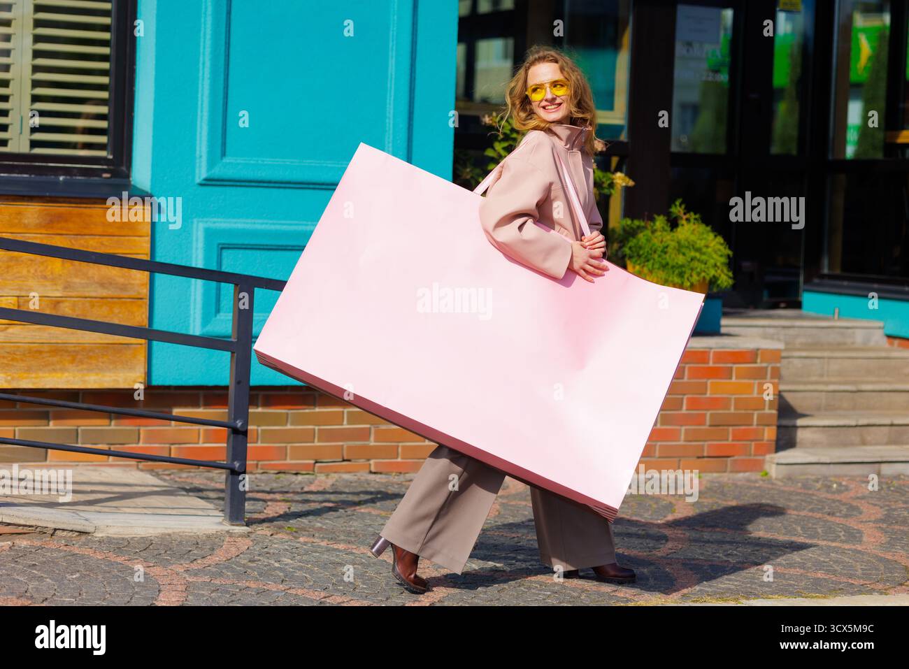 Frau trägt eine übergroße rosa Einkaufstasche im Freien, die Rabattverkäufe und Black Friday-Themen mit Kopierraum vorschlägt Stockfoto