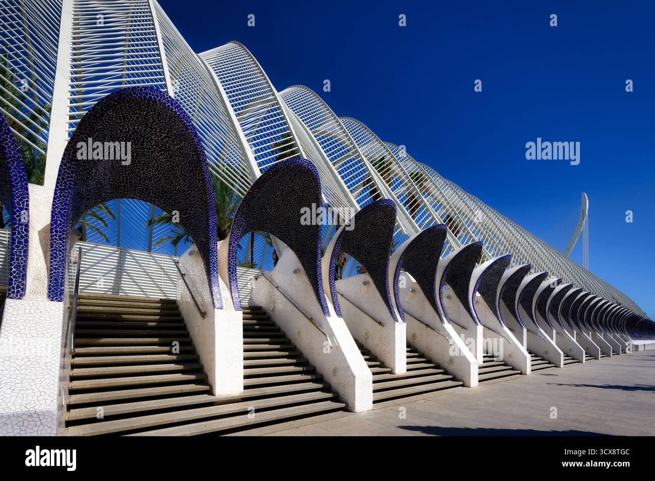 Die beeindruckende Architektur des Umbracle in Valencia, Spanien, mit Treppen, die zwischen weißen Säulen mit blauen Mosaikbögen hinaufführen Stockfoto