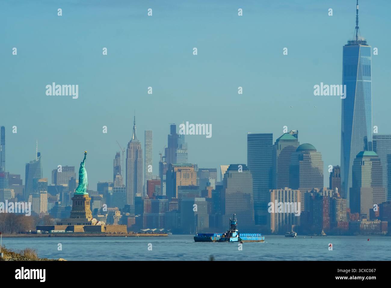 Panoramablick auf die Freiheitsstatue und die Skyline von Manhattan unter klarem blauem Himmel mit den berühmten Wahrzeichen von New York City und dem modernen Wasser Stockfoto