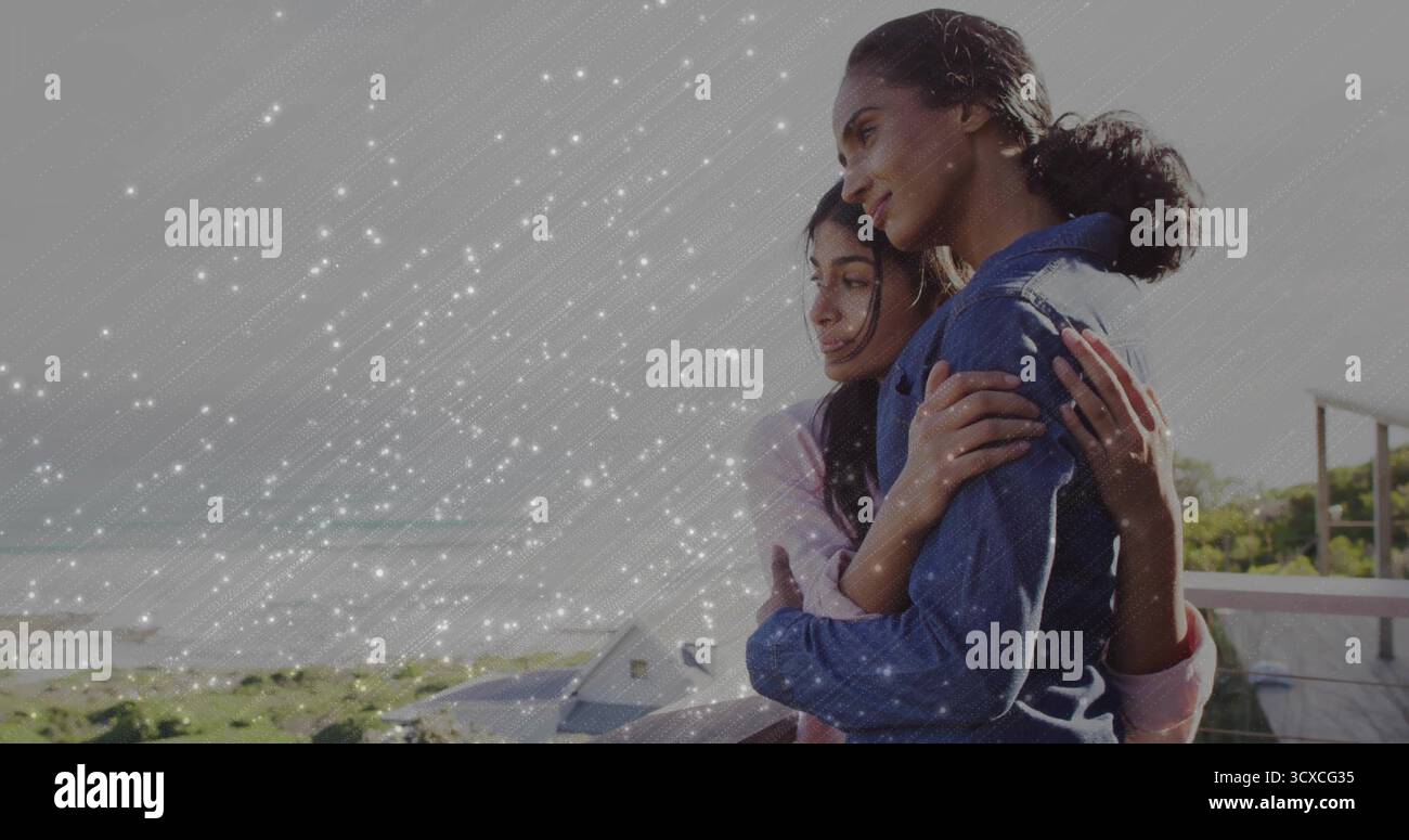 Liegende Mutter und Tochter mit Balkongeländer mit Blick auf die Meereswellen und die Häuser an der Küste Stockfoto