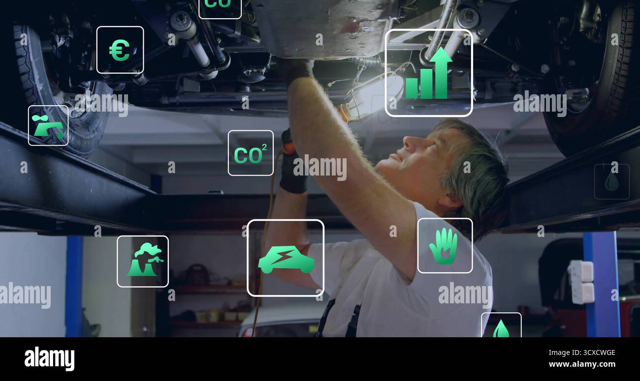 Bohrmechaniker mit Bohrmaschine unter dem Fahrzeugrahmen in der Werkstatt, mit Überlagerungssymbolen Stockfoto