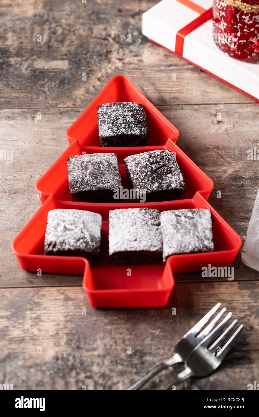 Schokoladen-Brownies mit Puderzucker in Tannenschale auf Holztisch Stockfoto