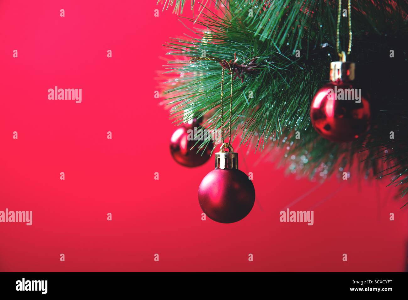 Rote Weihnachtskugeln auf Weihnachtsbaum auf rotem Hintergrund Stockfoto