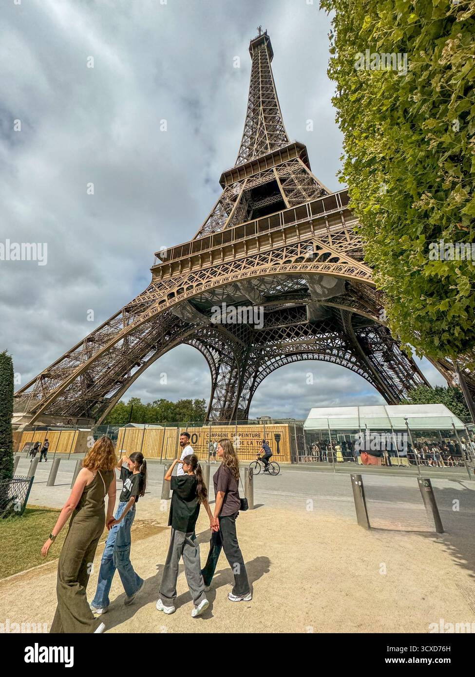 Touristenmassen am Fuße des Eiffelturms in Paris, Frankreich, an einem bewölkten Sommertag. Legendäres Wahrzeichen und Reiseziel der Welt - Smartphone-aufgenommenes Stockfoto