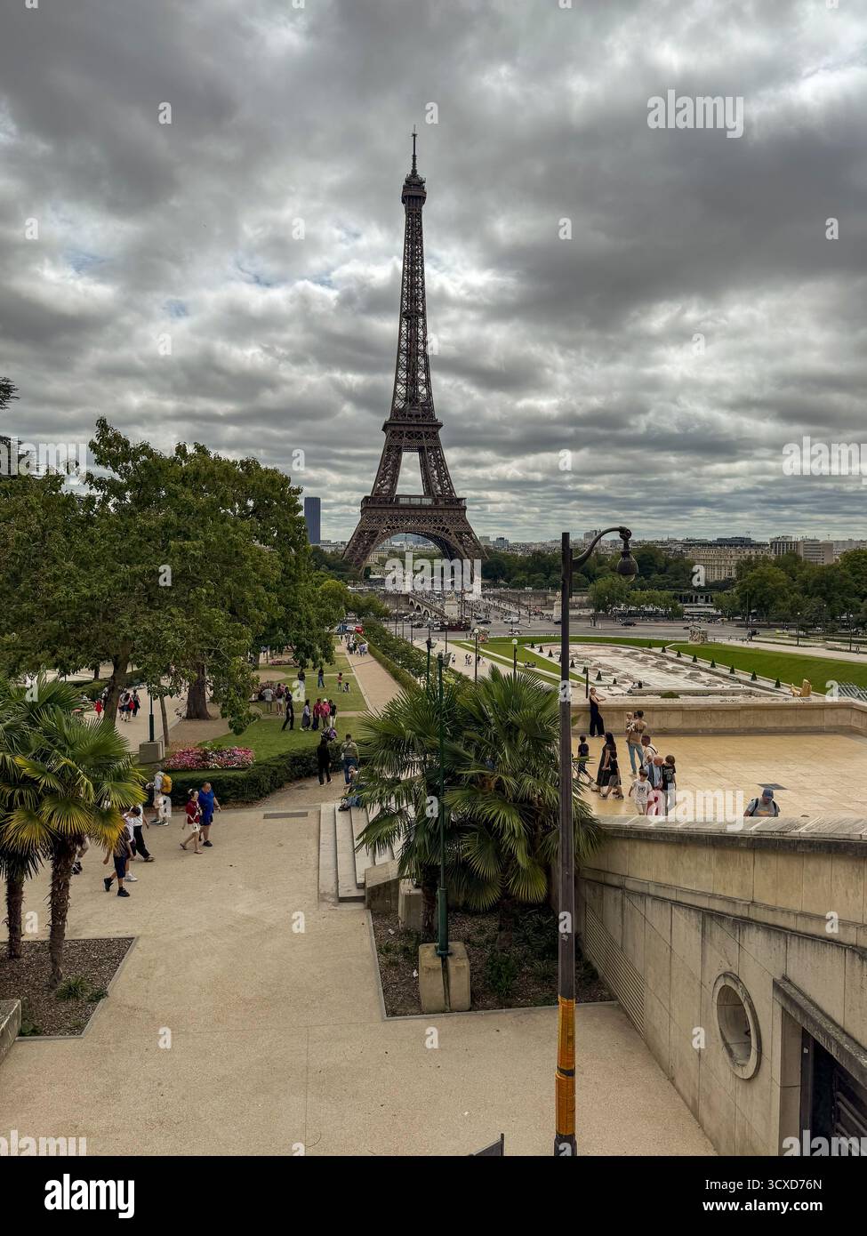 Großer erhöhter Blick vom Eiffelturm aus den Trocadéro-Gärten, Paris. Touristen wandern zwischen Terrassen, Springbrunnen und bewölktem dramatischem Himmel. Stockfoto