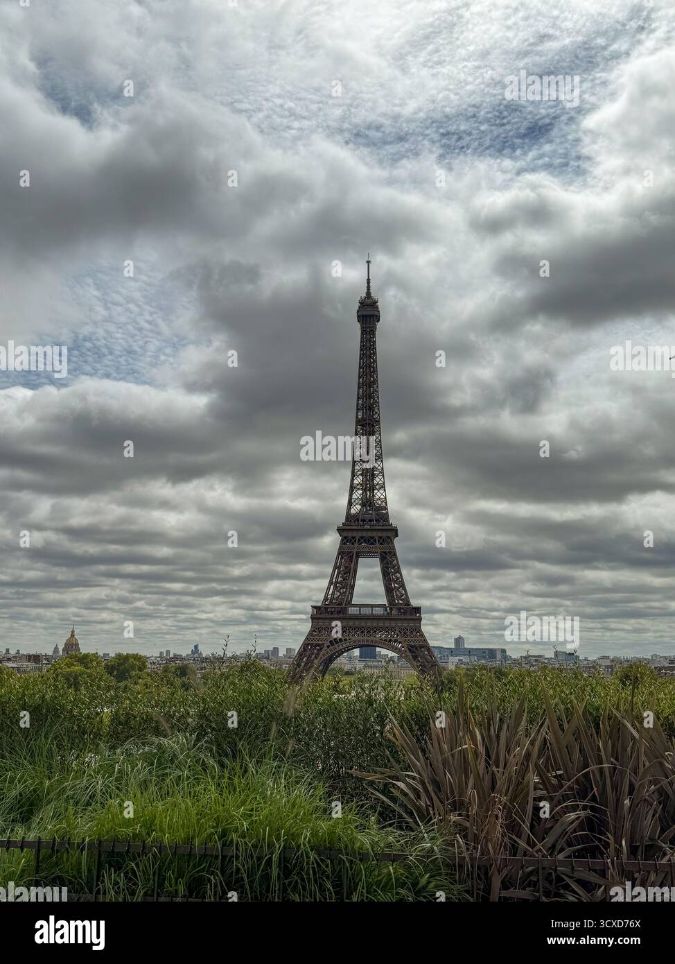 Ein großer Blick auf den berühmten Eiffelturm in Paris, Frankreich, der sich vor einem dramatischen bewölkten Himmel erhebt. - Smartphone-aufgenommenes Stockfoto