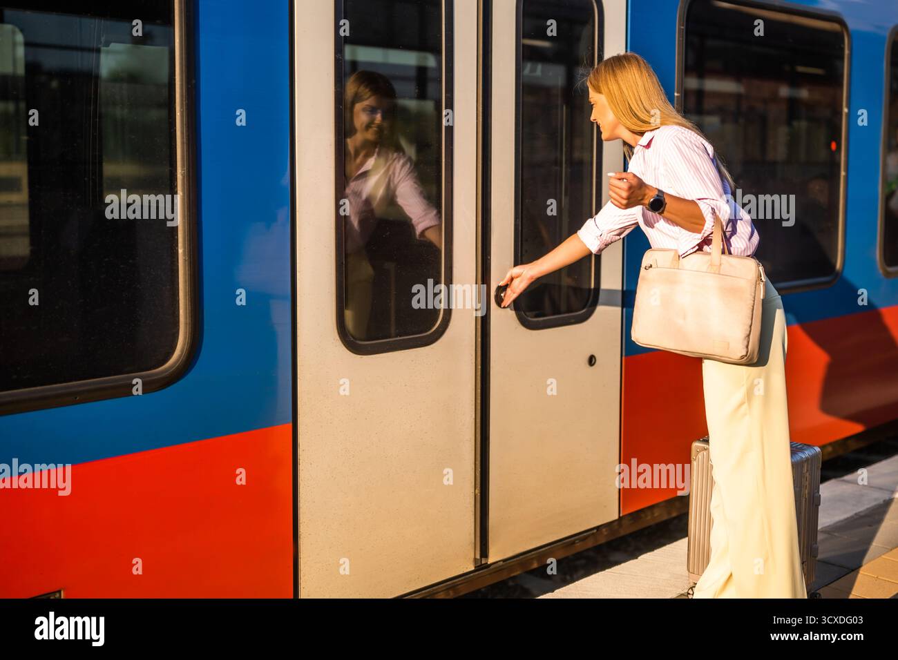 Elegante und selbstbewusste Geschäftsfrau, die am Bahnhof mit Koffer in einen Zug einsteigt. Stockfoto