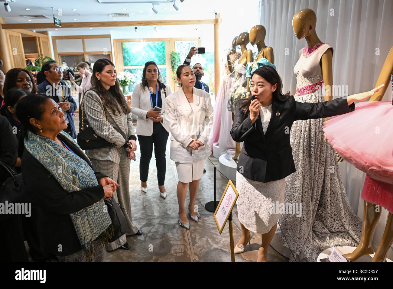 Peking, China. Oktober 2025. Vertreter, die sich für das Global Leaders' Meeting on Women in Peking aufhalten, erfahren mehr über Haute Couture-Kleidung während eines Besuchs im Gebäude der Seidenstraße in Peking, der Hauptstadt Chinas, am 14. Oktober 2025. Quelle: Zou Jingyi/Xinhua/Alamy Live News Stockfoto