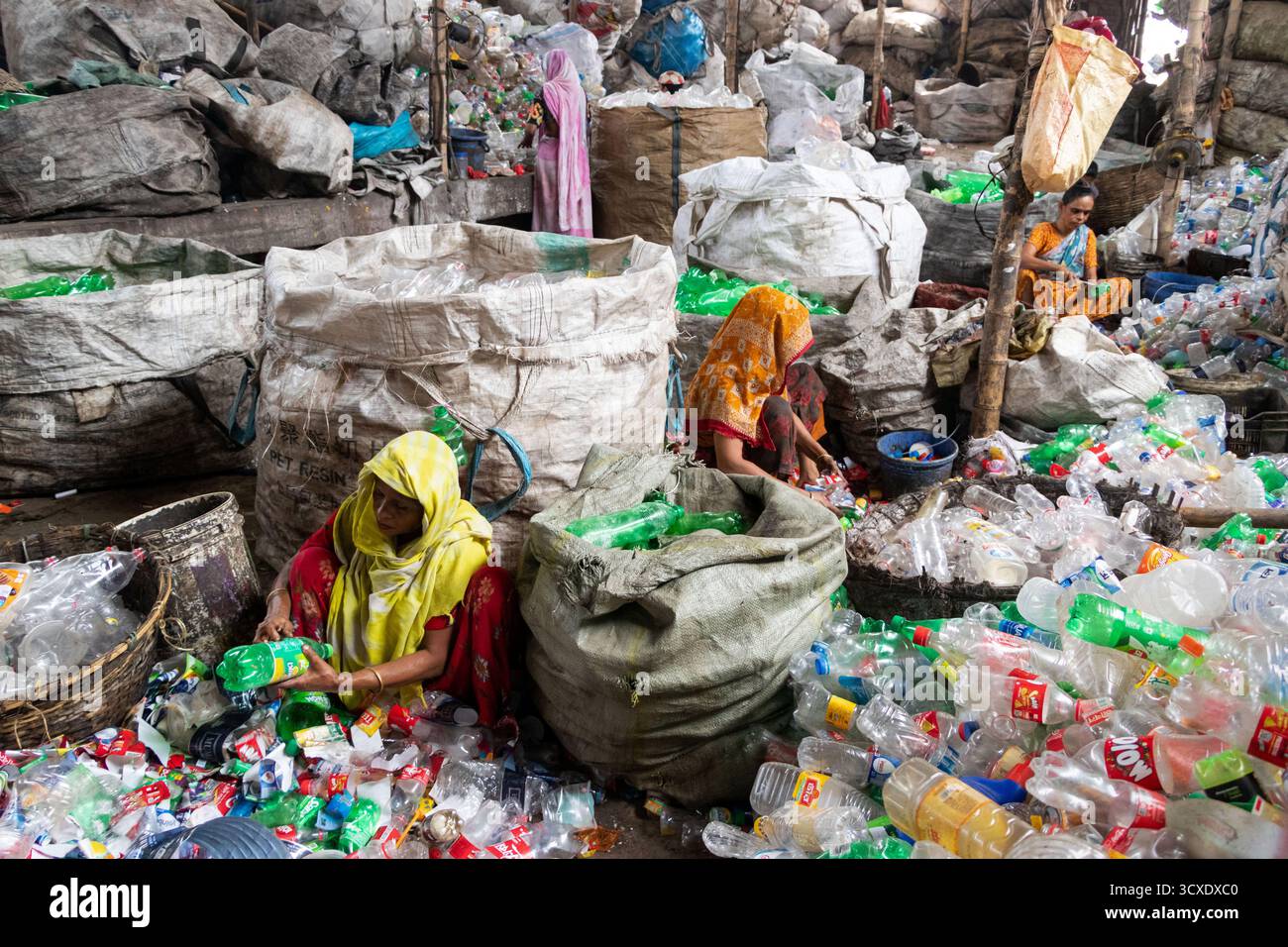 Dhaka, Dhaka, Bangladesch. Oktober 2025. Arbeiter sortieren gebrauchte Plastikflaschen in einer Recyclingfabrik in Dhaka, Bangladesch. Sie tragen dazu bei, zu verhindern, dass die Flaschen entsorgt, auf Deponien verbracht werden, wo sie bis zu 1.000 Jahre für den biologischen Abbau benötigen oder verbrannt werden, wodurch giftige Dämpfe entstehen. Die Emissionen von CO2 und anderen Treibhausgasen werden verringert, wenn bei der Herstellung neuer Kunststoffe Recycling stattfindet. Quelle: ZUMA Press, Inc./Alamy Live News Stockfoto