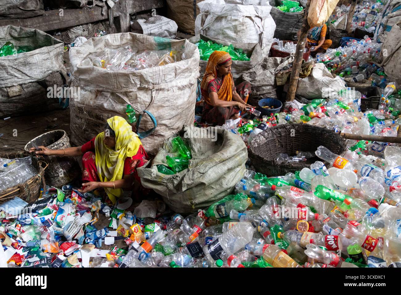 Dhaka, Dhaka, Bangladesch. Oktober 2025. Arbeiter sortieren gebrauchte Plastikflaschen in einer Recyclingfabrik in Dhaka, Bangladesch. Sie tragen dazu bei, zu verhindern, dass die Flaschen entsorgt, auf Deponien verbracht werden, wo sie bis zu 1.000 Jahre für den biologischen Abbau benötigen oder verbrannt werden, wodurch giftige Dämpfe entstehen. Die Emissionen von CO2 und anderen Treibhausgasen werden verringert, wenn bei der Herstellung neuer Kunststoffe Recycling stattfindet. Quelle: ZUMA Press, Inc./Alamy Live News Stockfoto