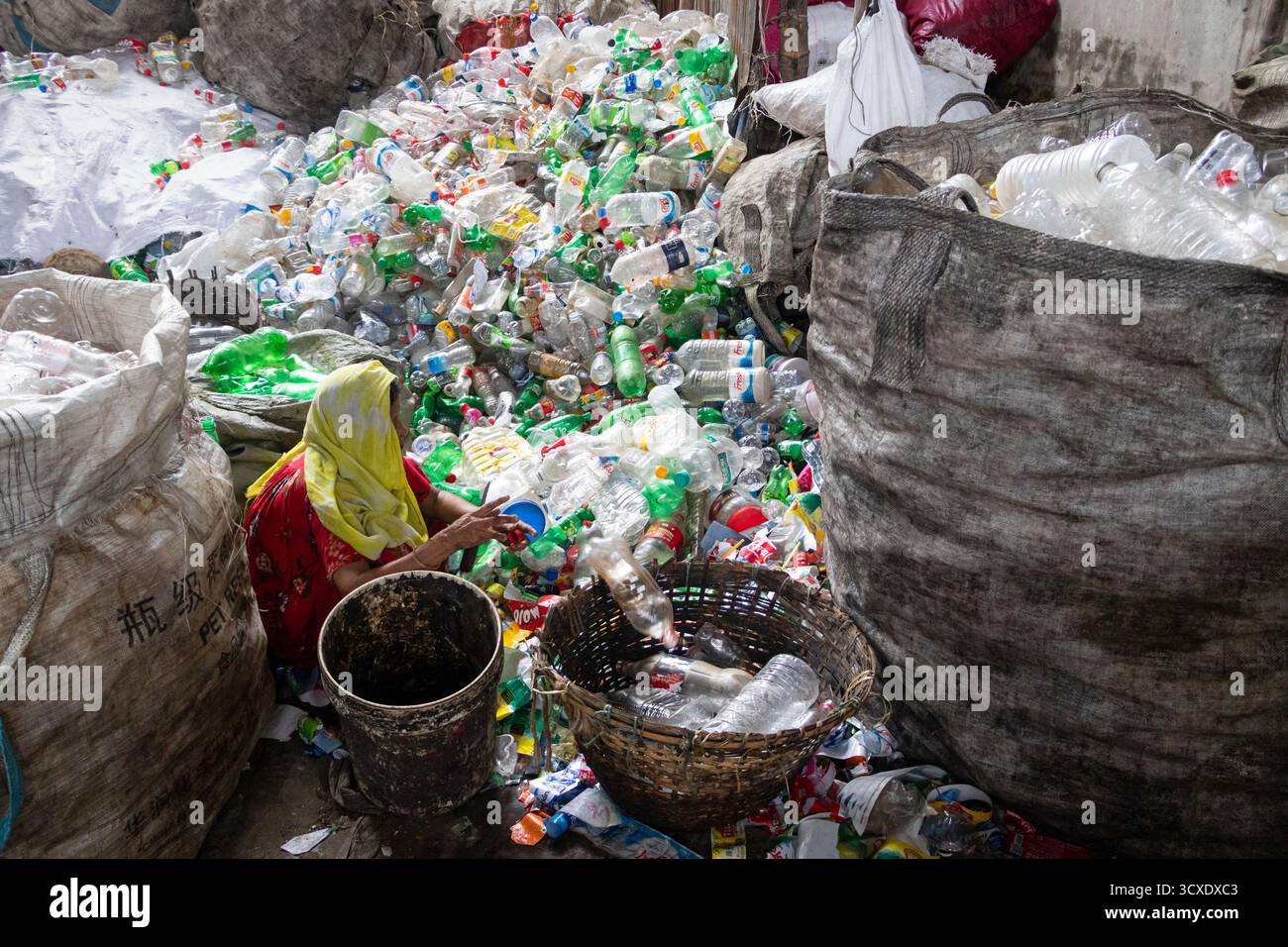 Dhaka, Dhaka, Bangladesch. Oktober 2025. Arbeiter sortieren gebrauchte Plastikflaschen in einer Recyclingfabrik in Dhaka, Bangladesch. Sie tragen dazu bei, zu verhindern, dass die Flaschen entsorgt, auf Deponien verbracht werden, wo sie bis zu 1.000 Jahre für den biologischen Abbau benötigen oder verbrannt werden, wodurch giftige Dämpfe entstehen. Die Emissionen von CO2 und anderen Treibhausgasen werden verringert, wenn bei der Herstellung neuer Kunststoffe Recycling stattfindet. Quelle: ZUMA Press, Inc./Alamy Live News Stockfoto