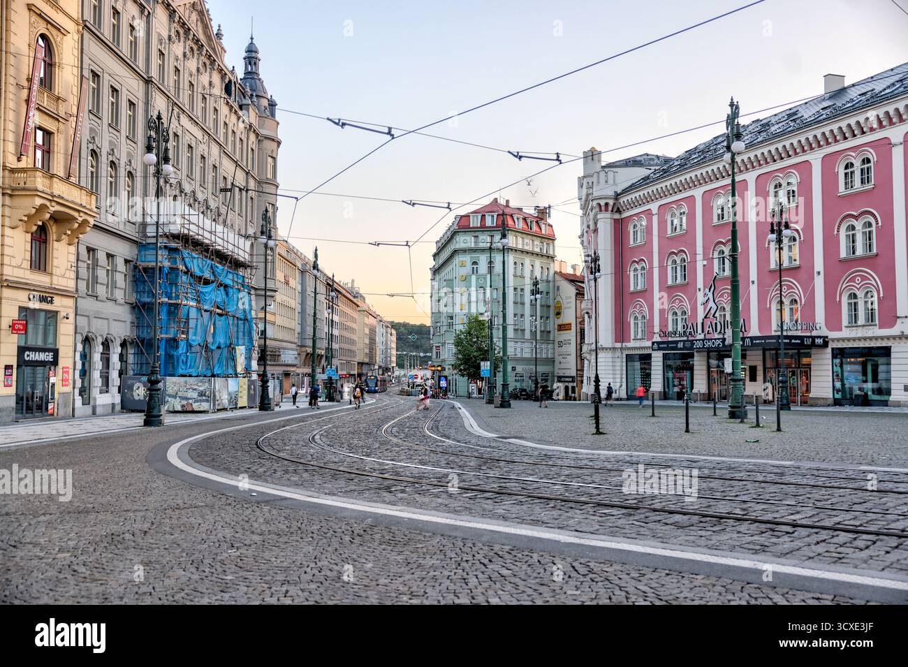 Straßenbahnen und Fußgänger am Jungmannovo-Platz im Zentrum von Prag, mit farbenfrohen historischen Gebäuden und Straßenbahnleitungen an einem bewölkten Tag. Stockfoto