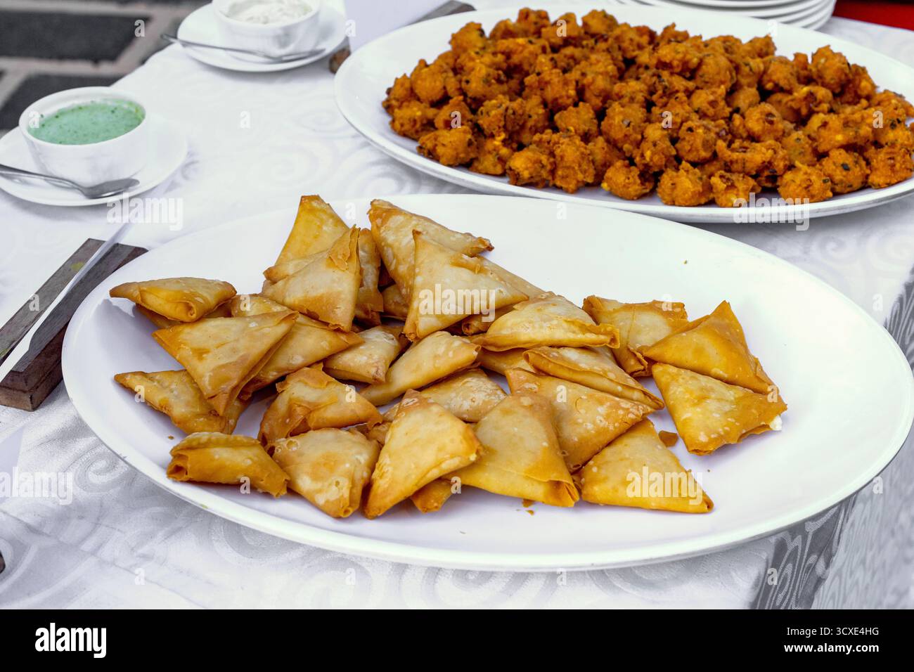 Köstliche indische Samosas und Vorspeisen serviert auf einer weißen Platte Stockfoto