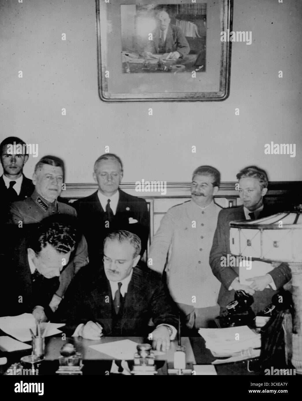 MOSKAU, RUSSLAND - 23. August 1939 - der sowjetische Außenkommissar Wjatscheslaw Molotow unterzeichnet den deutsch-sowjetischen Nichtangriffspakt im Kreml in Moskau. Hinter ihm stehen Joachim von Ribbentrop und Josef Stalin. Der vertrag gab den Deutschen die freie Hand, um ohne sowjetische Intervention in Polen einzumarschieren, und beinhaltete auch eine Zersplitterung Osteuropas, wenn die Nazis den Zweiten Weltkrieg gewonnen hätten - Foto: Geopix Stockfoto