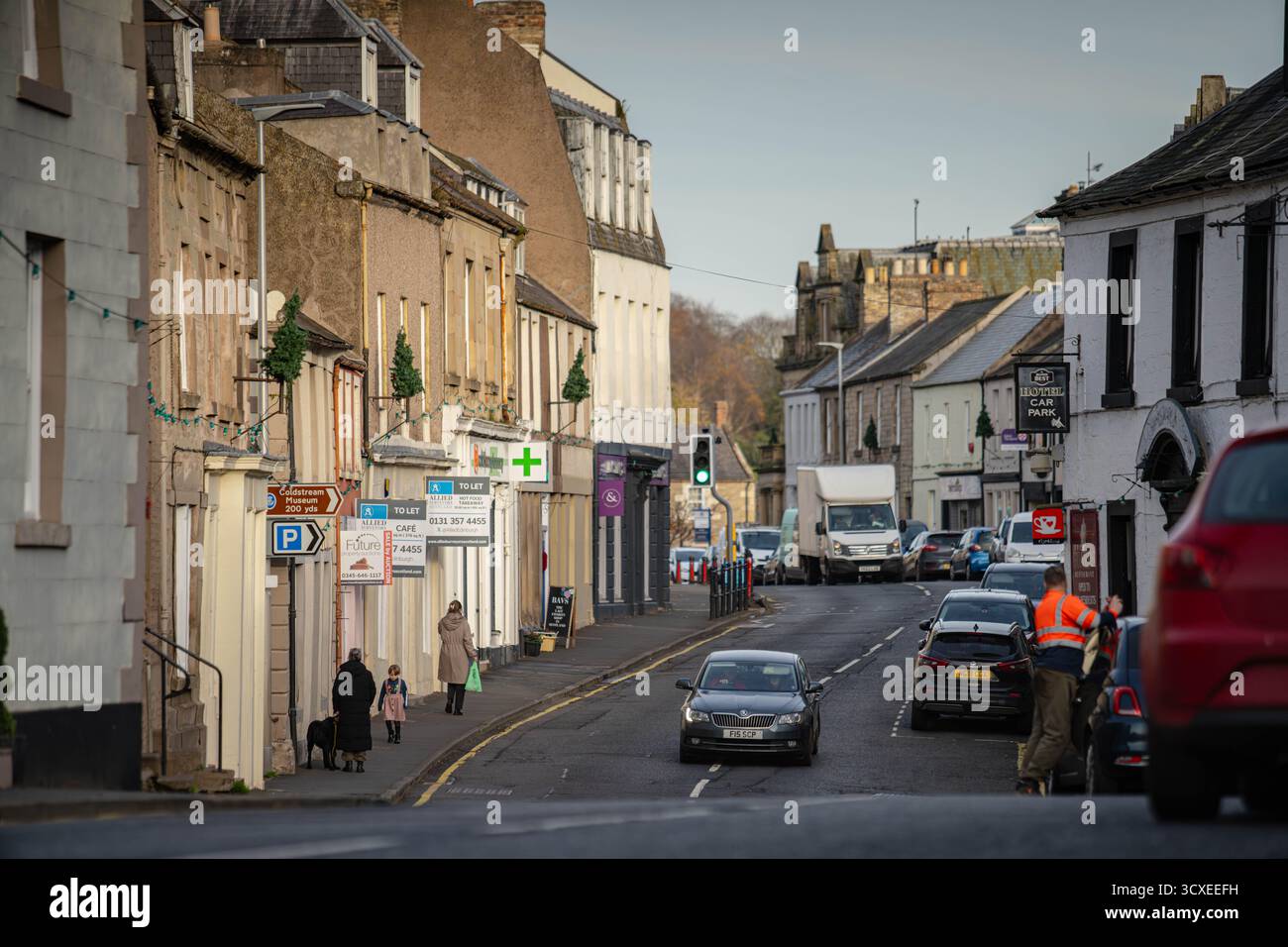 Blick auf die Straße entlang der High Street in Coldstream, einer historischen Stadt an der schottischen Grenze, Schottland, mit traditionellen Gebäuden, lokalen Geschäften und dem Schlepptau Stockfoto