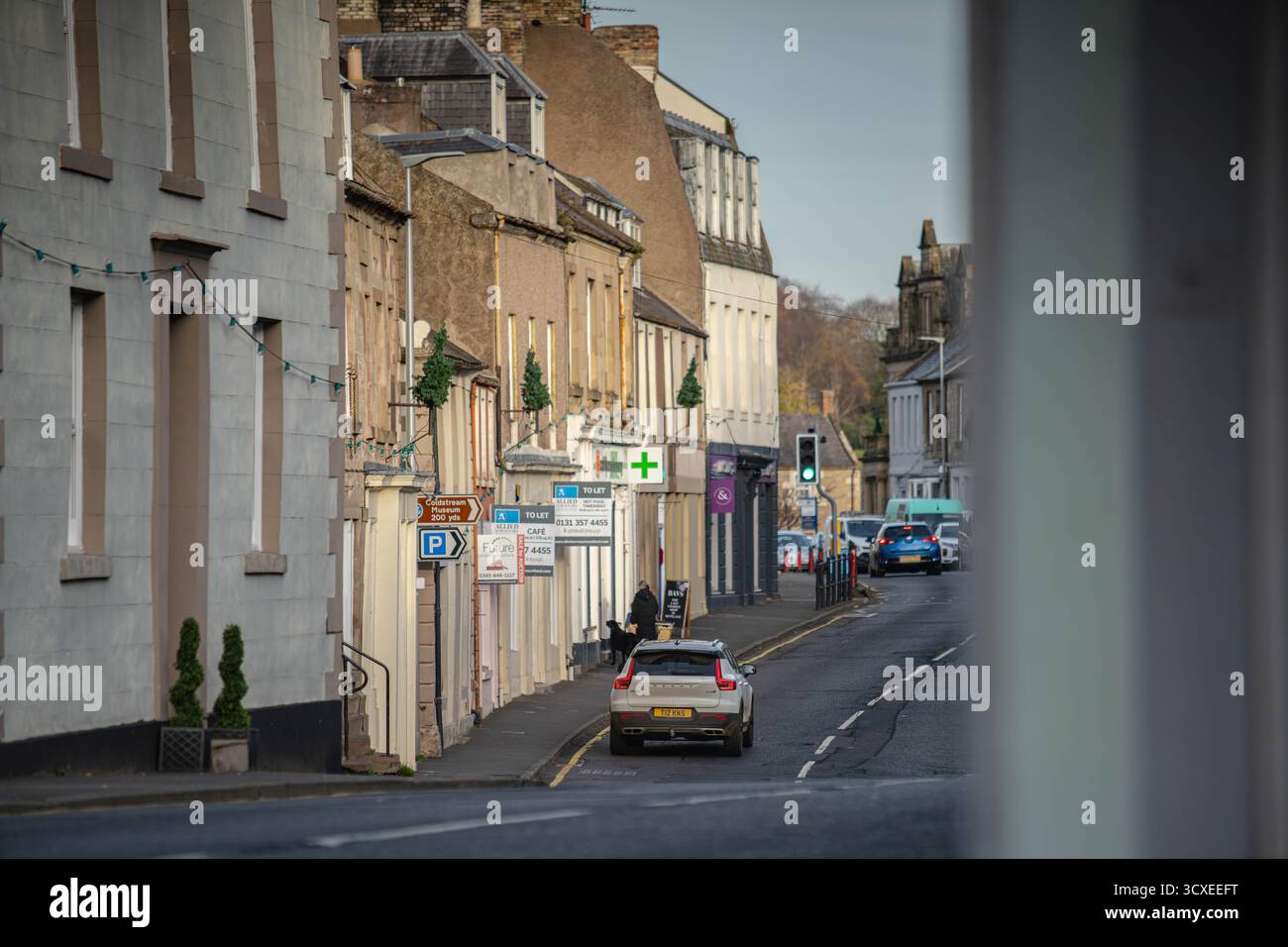 Blick auf die Straße entlang der High Street in Coldstream, einer historischen Stadt an der schottischen Grenze, Schottland, mit traditionellen Gebäuden, lokalen Geschäften und dem Schlepptau Stockfoto