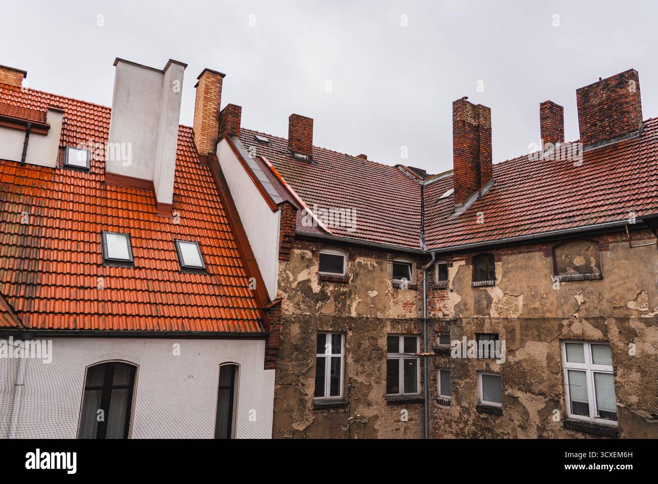 Die obersten Stockwerke des Mietshauses mit einem sichtbaren Ziegeldach Stockfoto