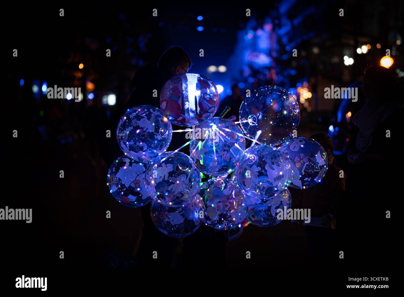Transparente Ballons mit blauen LED-Lichtern, die bei einem Lichtfestival im Dunkeln leuchten, schaffen eine magische und farbenfrohe nächtliche Atmosphäre. Stockfoto
