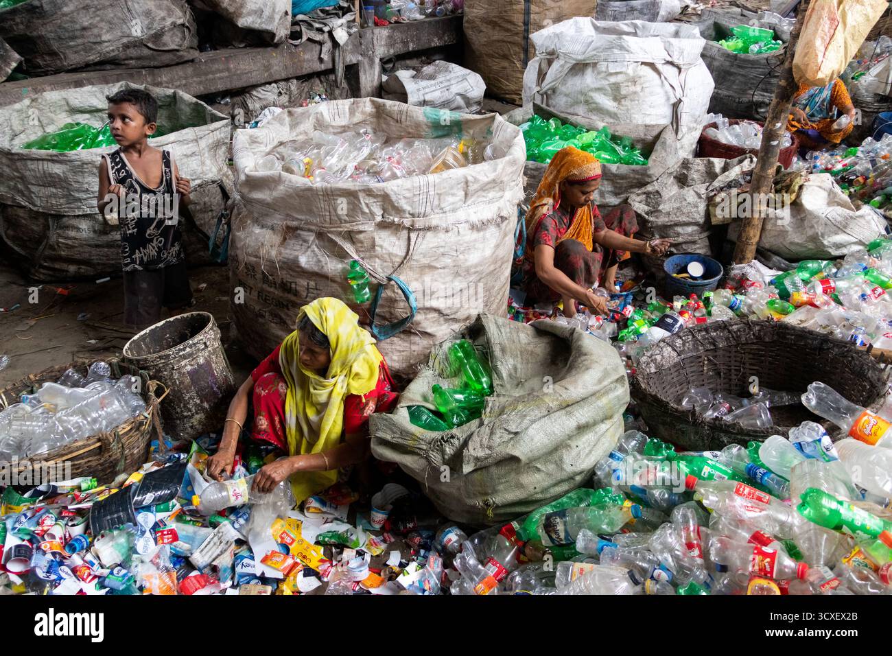 14. Oktober 2025, Dhaka, Bangladesch: Arbeiter sortieren gebrauchte Plastikflaschen in einer Recyclingfabrik in Dhaka, Bangladesch. Sie tragen dazu bei, zu verhindern, dass die Flaschen entsorgt, auf Deponien verbracht werden, wo sie bis zu 1.000 Jahre für den biologischen Abbau benötigen oder verbrannt werden, wodurch giftige Dämpfe entstehen. Die Emissionen von CO2 und anderen Treibhausgasen werden verringert, wenn bei der Herstellung neuer Kunststoffe Recycling stattfindet. Dieser kleine, aber bedeutende Akt unterstützt die ökologische Nachhaltigkeit, indem er einen verantwortungsvollen Zyklus der Wiederverwendung fördert, die Belastung der natürlichen Ressourcen verringert und unser Ökosystem für die Zukunft schützt Stockfoto