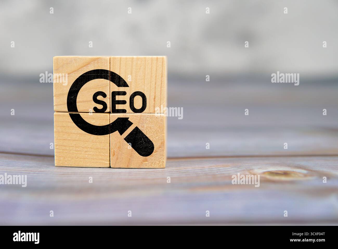 SEO-Text mit Lupensymbol auf Holzwürfeln, die auf einem Holztisch platziert werden, symbolisiert die Suchmaschinenoptimierung. Stockfoto