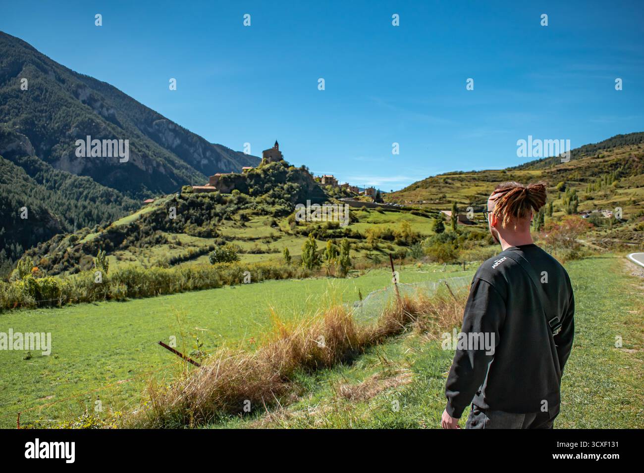 Eine Person, die in einem malerischen katalonischen Dorf in Spanien steht, umgeben von umliegenden Bergen und sanften Hügeln. Stockfoto