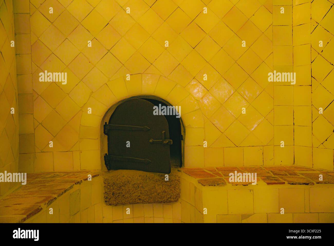 Gelb geflieste Wand mit gefliesten Bänken, Kamin, Ofen, in einer Sauna Stockfoto