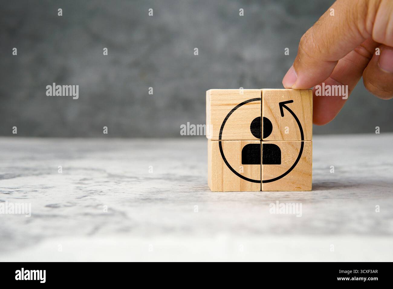 Holzwürfel mit Symbol des Benutzers und kreisförmigem Pfeil, die Kundenbindung, wiederholten Kauf und Benutzerloyalität in der Marketingstrategie symbolisieren. Stockfoto