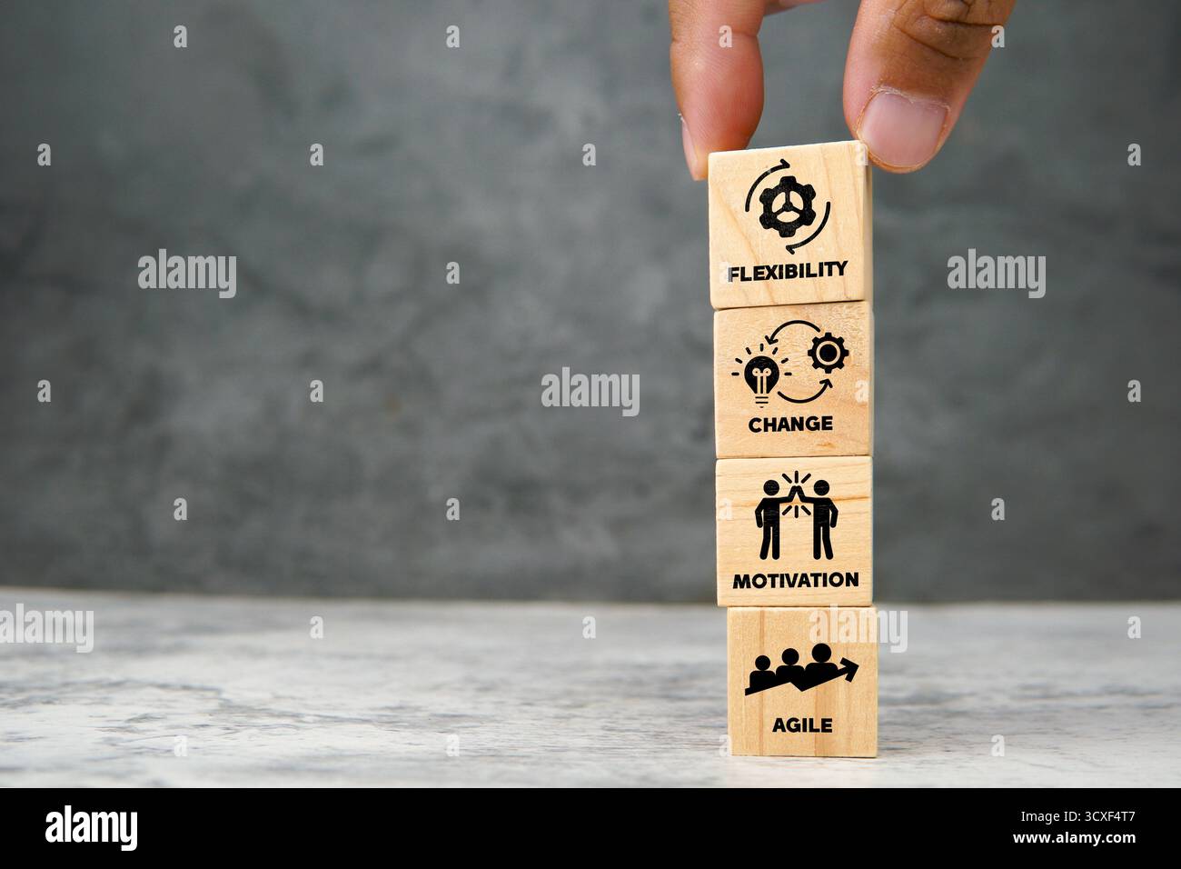 Vertikal gestapelte Holzwürfel mit Symbolen für Flexibilität, Veränderung, Motivation und agiles Teamwork. Konzept der Unternehmenstransformation. Stockfoto