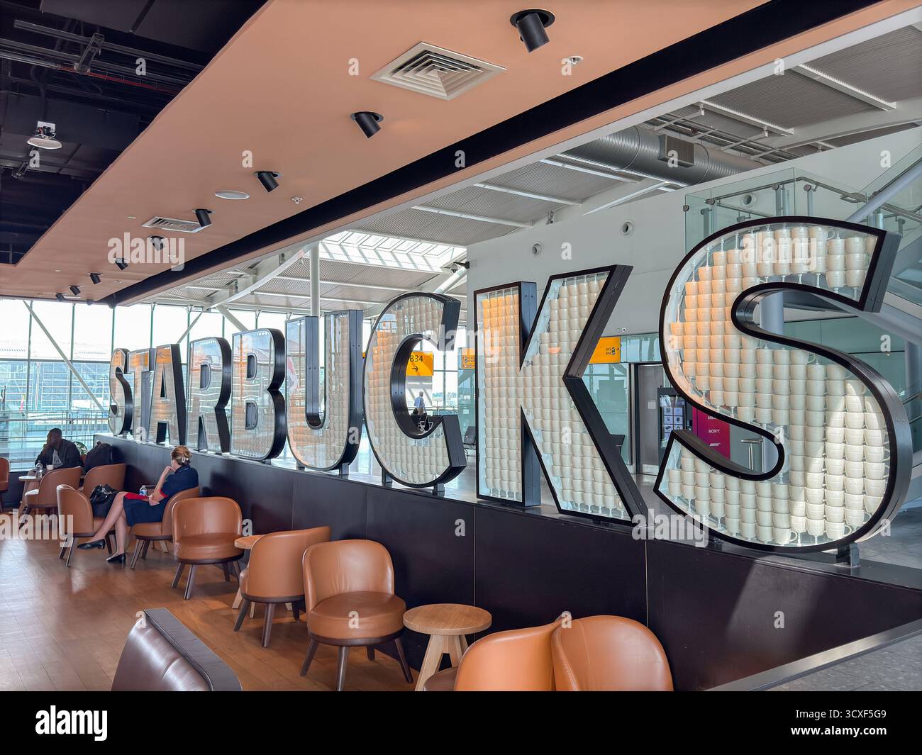 London, England, Großbritannien - 20. Mai 2025: Starbucks Coffee Shop in einem der Satellitenterminals des Terminals 5 am Flughafen London Heathrow - Smartphone-aufgenommenes Stockfoto