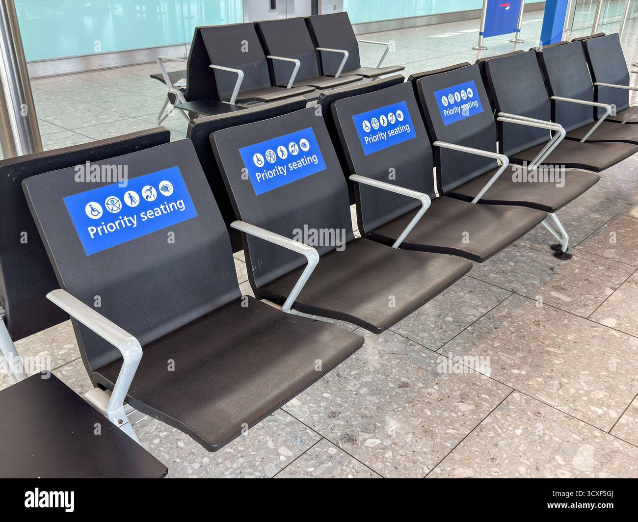 London, England, Großbritannien - 19. Mai 2025: Sitzplätze in einem Flughafenterminal mit einem Schild für bevorzugte Sitzplätze und Symbolen für Personen, die Hilfe benötigen. Keine Personen. Stockfoto