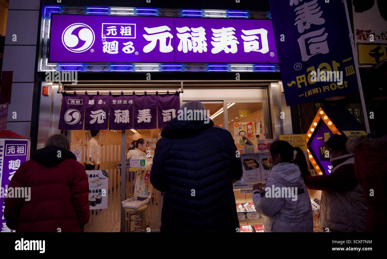 Die Leute stehen vor einem Genrokuzushi-Sushi-Restaurant in Osaka an Stockfoto