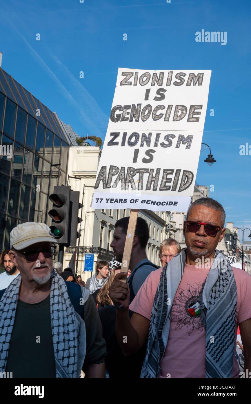 Nationale Demonstration für Palästina, London. Demonstranten mit dem Zeichen "Zionismus ist Völkermord, Zionismus ist Apartheid". Stockfoto