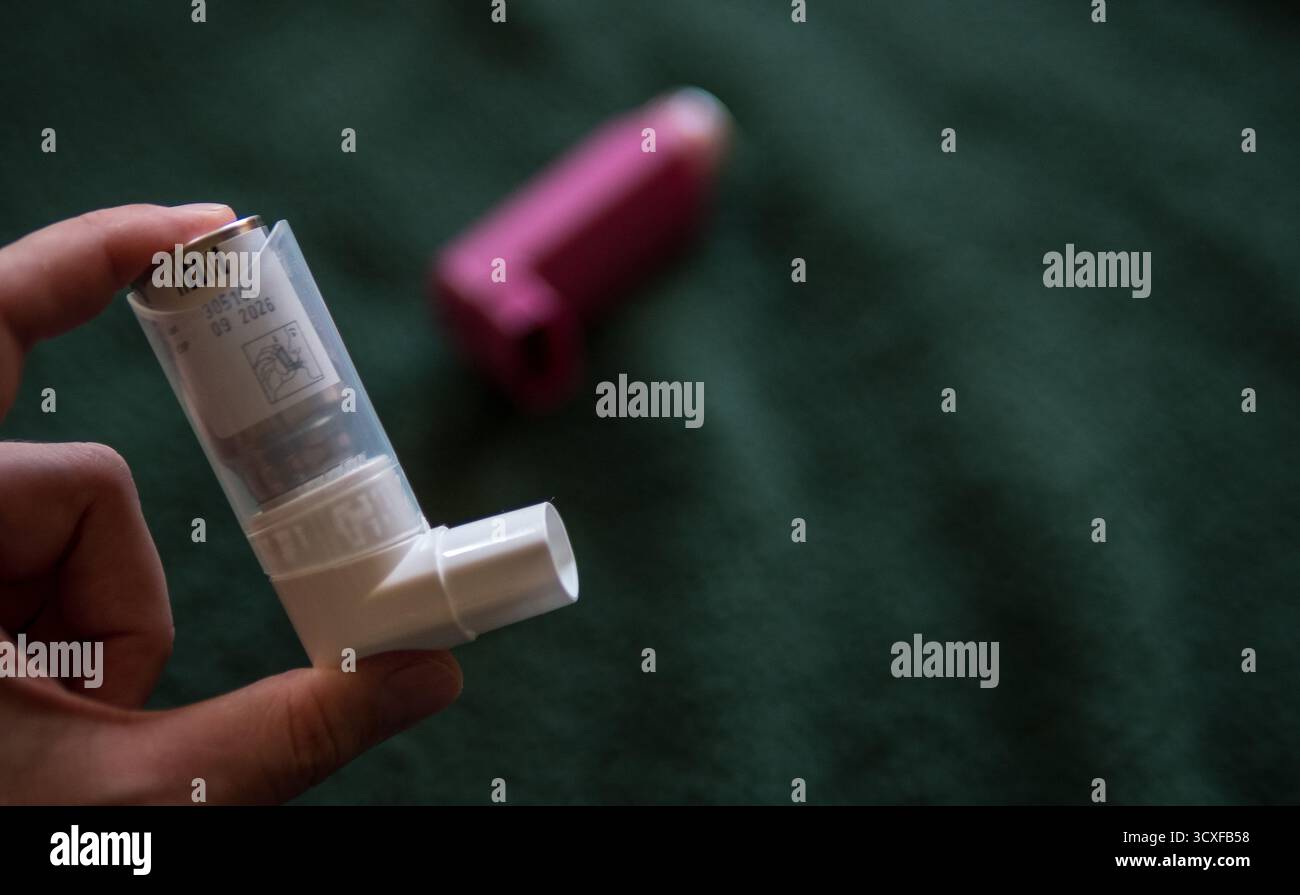 Hand hält Asthma-Inhalator auf dunklem Hintergrund Stockfoto