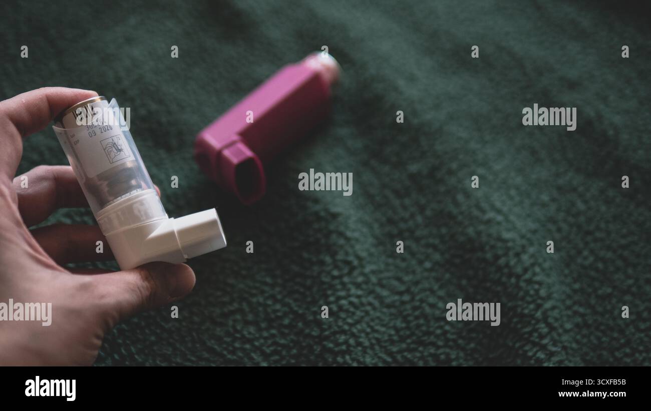Hand hält Asthma-Inhalator auf dunklem Hintergrund Stockfoto
