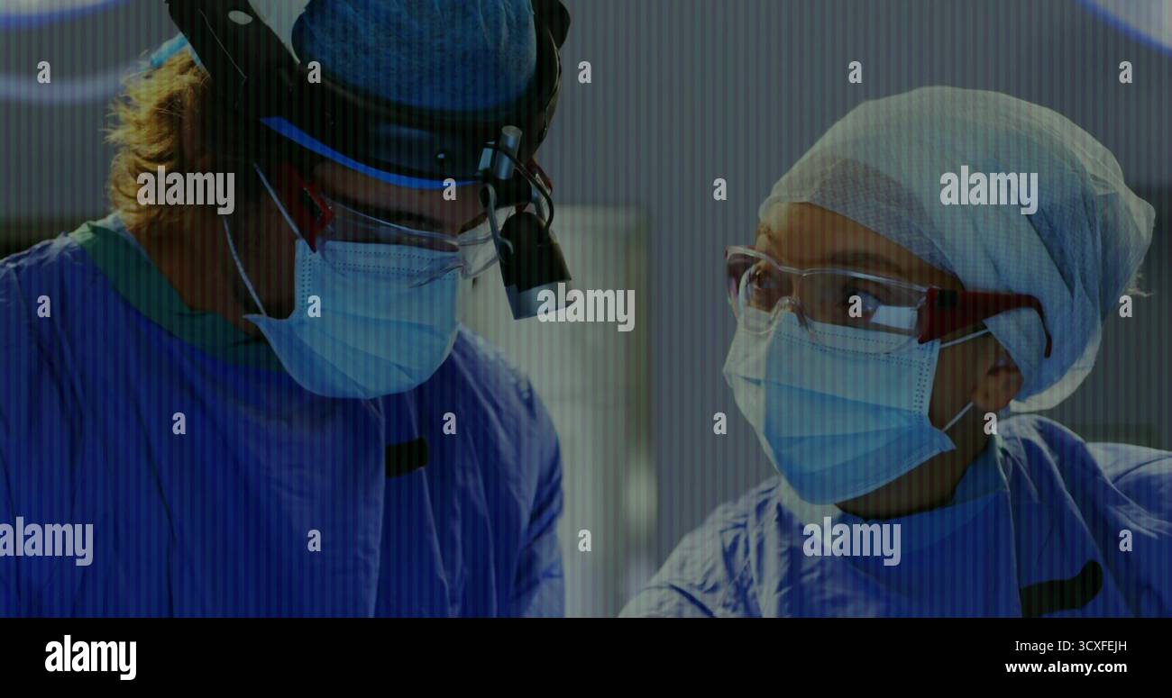 Operierende Chirurgen mit Peelings und Masken im Operationssaal mit Scheinwerferlupen Stockfoto